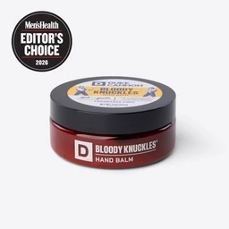 Bloody Knuckles Hand Balm container from a side angle. Badge in corner says Men's Health Editor's Choice 2026.