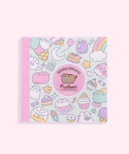 Pink-colored Pusheen coloring and activity book with pastel illustrations and a pink spine, shown closed on a light pink background.