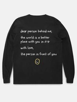 This is a black long-sleeve casual shirt with a handwritten-style white text print on the back. It features a small yellow smiley face graphic beneath the text. Likely unisex (model not clearly gendered); overall style is casual everyday wear with a positive, friendly message.