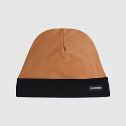 This is a two-tone, slouchy-style beanie with a camel/tan crown and a solid black cuff. The visible material on the crown looks smooth and synthetic, while the black turned-up cuff adds contrast and features a small Blackstrap label. Overall, a unisex knit beanie with a simple, minimalist look.
