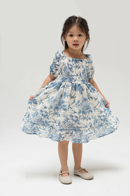 Mini Zoey Smocked Dress in blue floral print with puff sleeves, front view on child model.