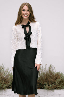 Monique Sequin Bow Jacket in cream worn over black dress, front view.