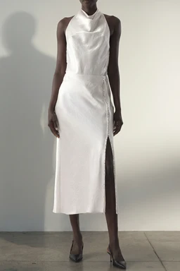 - A sleeveless white satin midi dress with a halter neckline and a high, wrapped waist. The front features a clean, tailored silhouette with a knee-length hem and a long, front-side slit for movement.
- Audience: women.
- Notable visible attributes: smooth white satin fabric with a slight sheen, halter neck design, wrap-style waist, and a leg-side slit. Although the title notes crystal straps, no straps or embellishments are visible on the model in this photo.