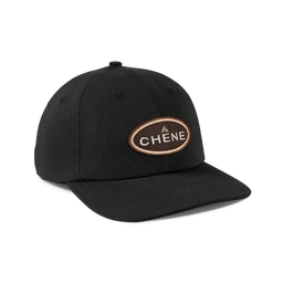 A black baseball cap with a curved brim and six-panel construction. Unisex in styling, with a brown oval patch featuring the word “CHENE” on the front. Appears to be a cotton/twill fabric with a simple, athletic wear look.