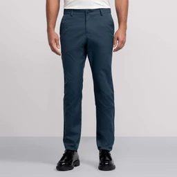 Against a plain background, a person wears Jack Archer's teal Jetsetter Tech Pant—water-repellent and wrinkle-resistant—paired with a white tucked-in shirt and black dress shoes. The photo is cropped from the shoulders down.