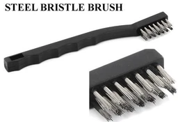 A black plastic-handled steel wire brush with rows of silver metal bristles, shown against a white background with a close-up of the bristle head.