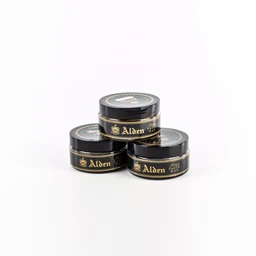 Three small black circular tins of wax polish are stacked in a pyramid on a white background. The tins feature gold lettering and a gold emblem along the label, suggesting a premium leather care product for men’s shoes. Visible attributes: black containers with gold text, plastic/lid tops, compact, polished presentation.