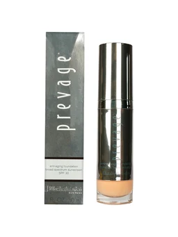 A silver-grey boxed Prevage anti-aging foundation bottle with a metallic pump-style cap and a light beige liquid visible through its clear base, shown beside its packaging box on a white background.