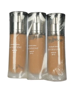 Three clear-wrapped bottles of tan-brown liquid foundation with silver pump caps and Elizabeth Arden Intervene labels, shown side by side on a white background.