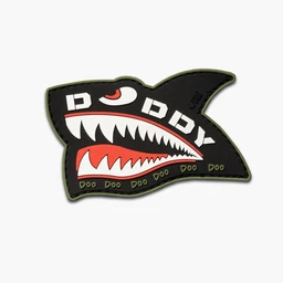 This is a cartoon embroidered patch in the shape of a shark head, designed to adorn clothing or accessories. It appears to be unisex, suitable for kids or adults, with a bold black background, white teeth and lettering, and a red mouth outlined in a light green edge. The stitching and patch borders are visible, giving a rugged, playful graphic style.