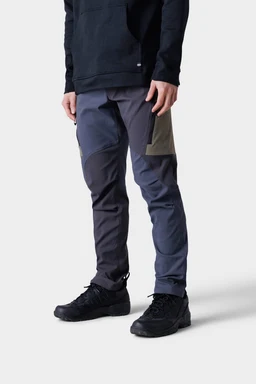 A person wearing a black hoodie, 686 Mens Anything Cargo Pant - Slim Fit by 686 in gray and olive with 13-pocket detailing, and black athletic shoes, stands against a plain light gray background.