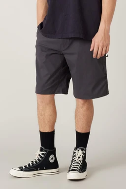 A person in 686 Men's Everywhere® Hybrid Short - Relaxed Fit (dark gray), a dark tee, black crew socks, and black high-top Converse stands against a plain light background. The image is cropped at the shoulders.