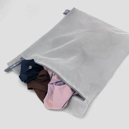 Light gray fabric delicates wash bag with a zipper, partially open to reveal colorful underwear inside.